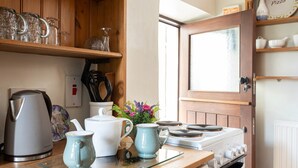 A kitchen with a stove, kettle, teapot, and mugs on the counter. - Cottage in Settle near Yorkshire Dales (Settle)