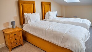 Une chambre avec deux lits, une table de chevet et une lucarne.