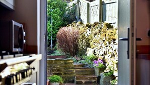 A narrow stone pathway leading to a garden with potted plants and a wooden fence. - Cottage in Bellerby with Private Hot Tub (Bellerby)