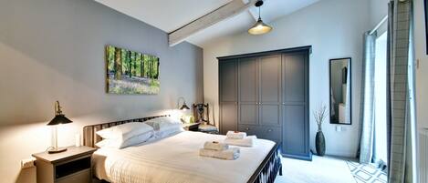 A bedroom with a bed, nightstand, dresser, and a painting on the wall.