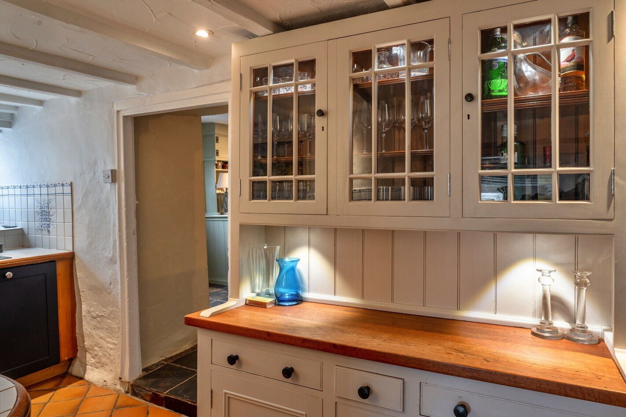 A kitchen with wooden cabinets, a countertop, and a door leading to another room.