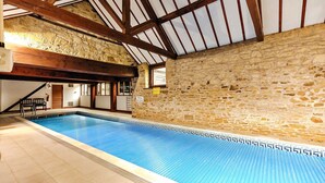 En indendørs swimmingpool med stenvægge og træbjælker.