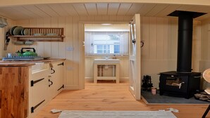 Una cocina acogedora con armarios de madera, una estufa integrada y una ventana con persianas.