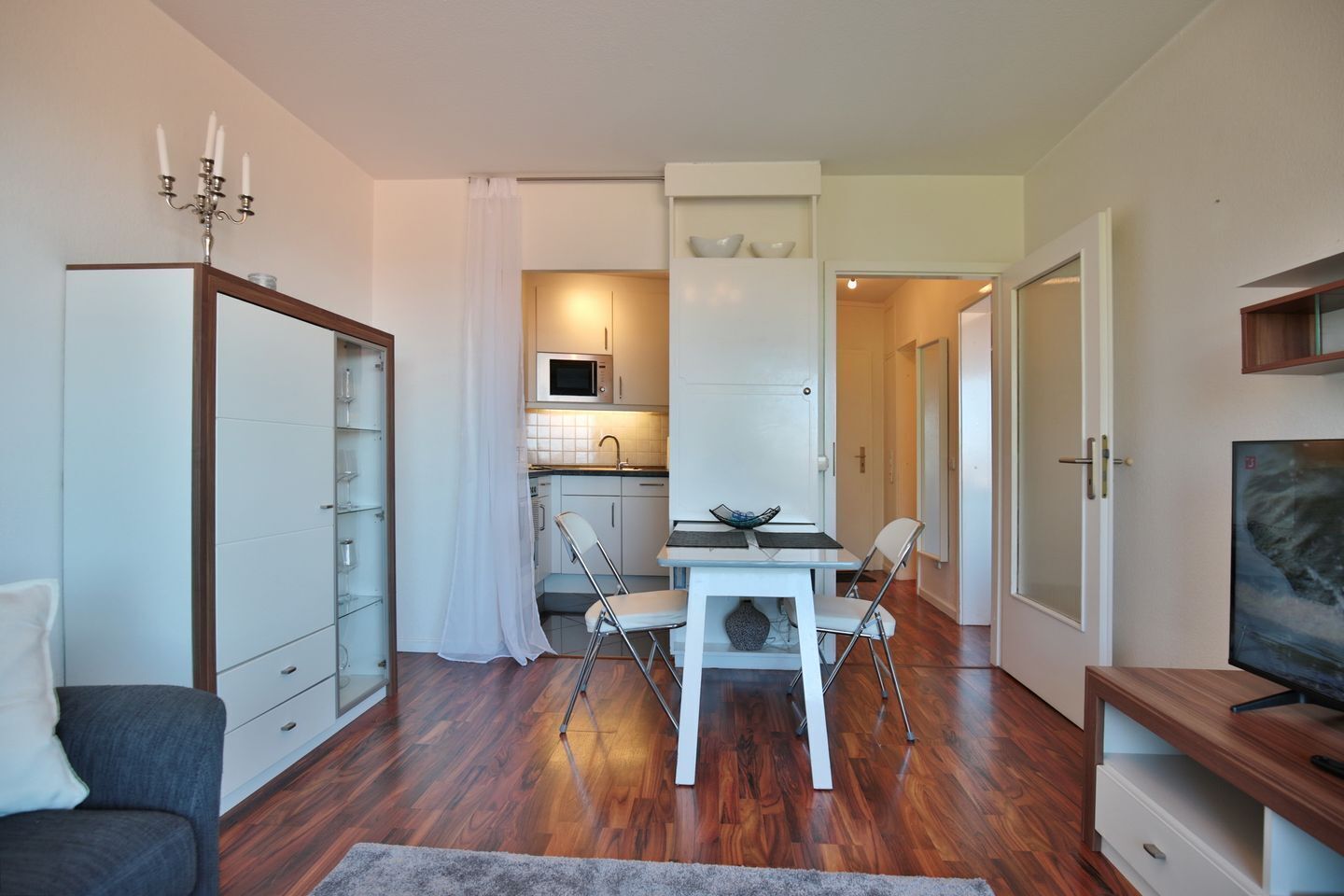 A compact living space with a kitchenette, a dining area, and a TV.