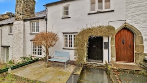 A traditional stone building with a wooden door, a bench, and a small garden area.