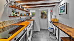 A compact kitchen with wooden countertops, a washing machine, and a small dining area.