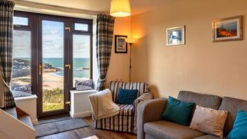 A living room with a sofa, armchairs, and a view of the sea through large windows.
