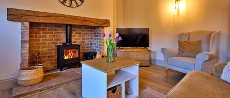 Cozy living room with a brick fireplace, comfortable sofa, and flat-screen TV.