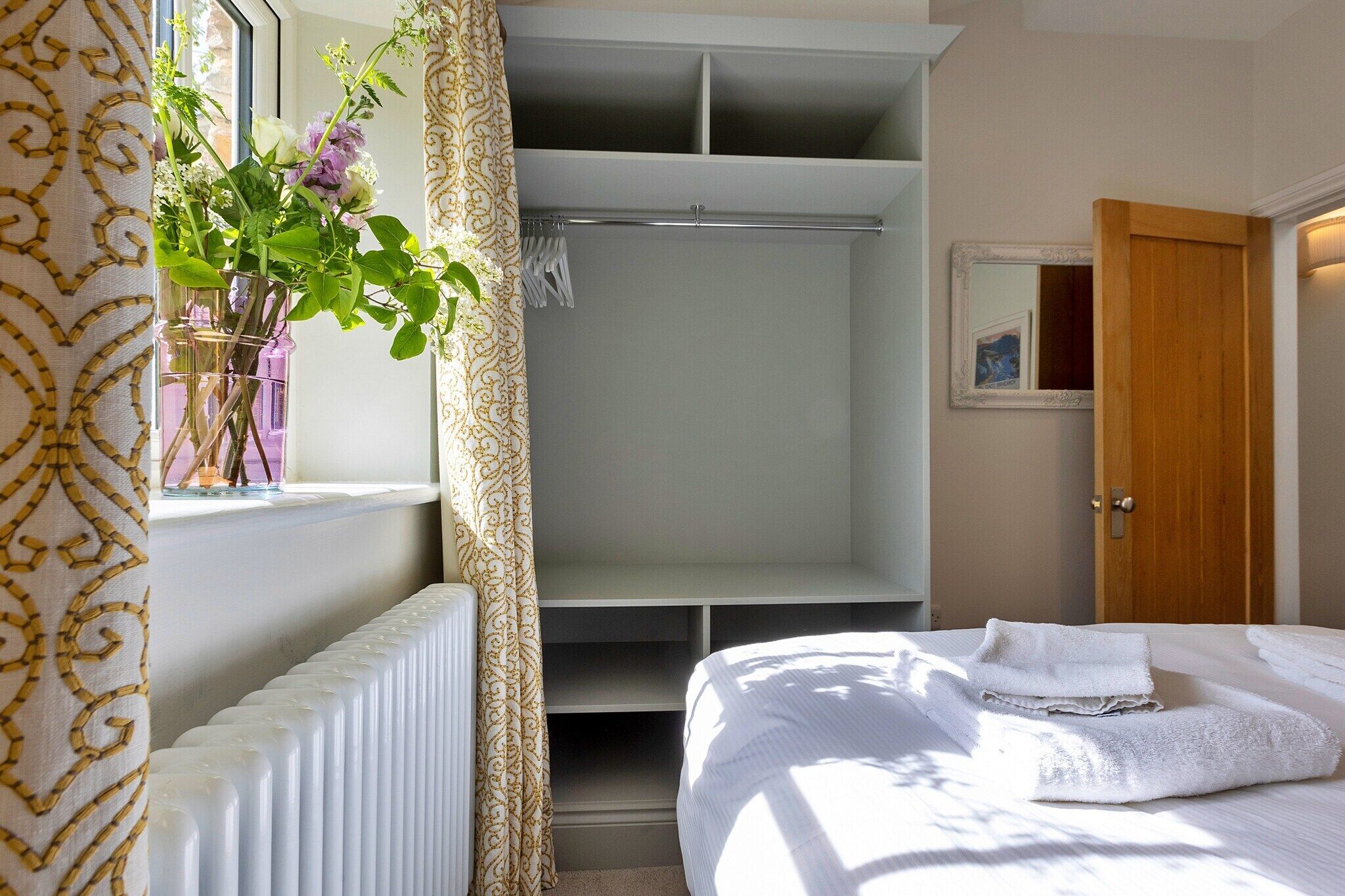 A hotel room with a bed, a wardrobe, a radiator, and a window with curtains.