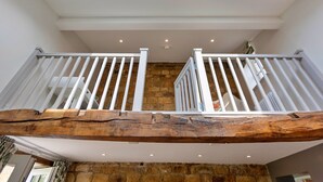 A spacious interior with a high ceiling, exposed wooden beams, and a stone wall. - Cottage in Grantley near Fountains Abbey (Grantley)