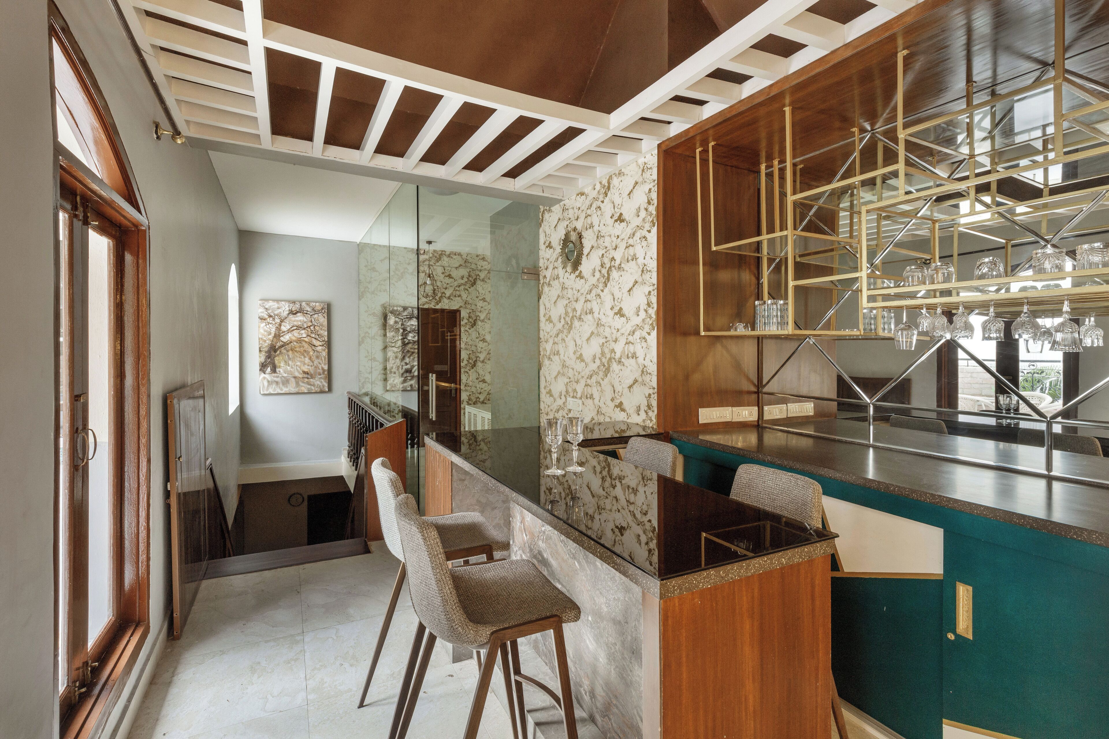 A modern kitchen with a marble countertop, bar stools, and a glass backsplash.