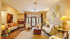 A spacious living room with a large window, a sofa, chairs, a coffee table, and decorative items.