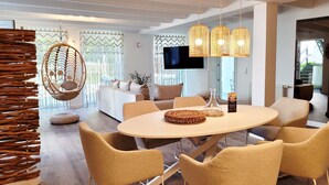 A modern dining area with a round table, four chairs, and hanging lights. - Modern lounge apartment with terrace, beach chair, parking - 50 meters to the beach (Sierksdorf)