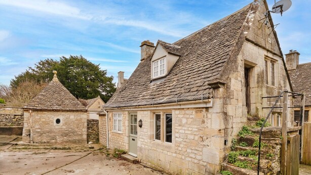 Un bâtiment en pierre doté d’un toit à forte pente, d’une petite fenêtre et d’une porte.