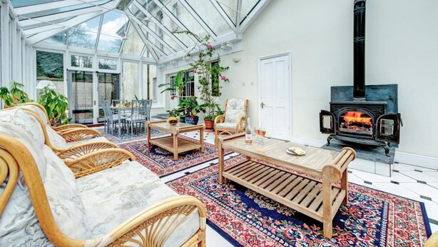 A conservatory with wicker furniture, a fireplace, and a large window. - Holiday home near Slapton Sands, No Deposit (Slapton)