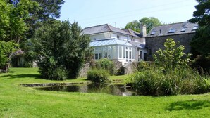 A house with a conservatory, a pond, and a stone wall. - Holiday home near Slapton Sands, No Deposit (Slapton)