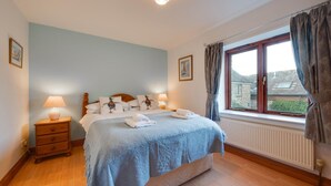 A bedroom with a bed, bedside lamps, a window with curtains, and a radiator. - Pet-friendly cottage in Slapton, No Deposit (Slapton)