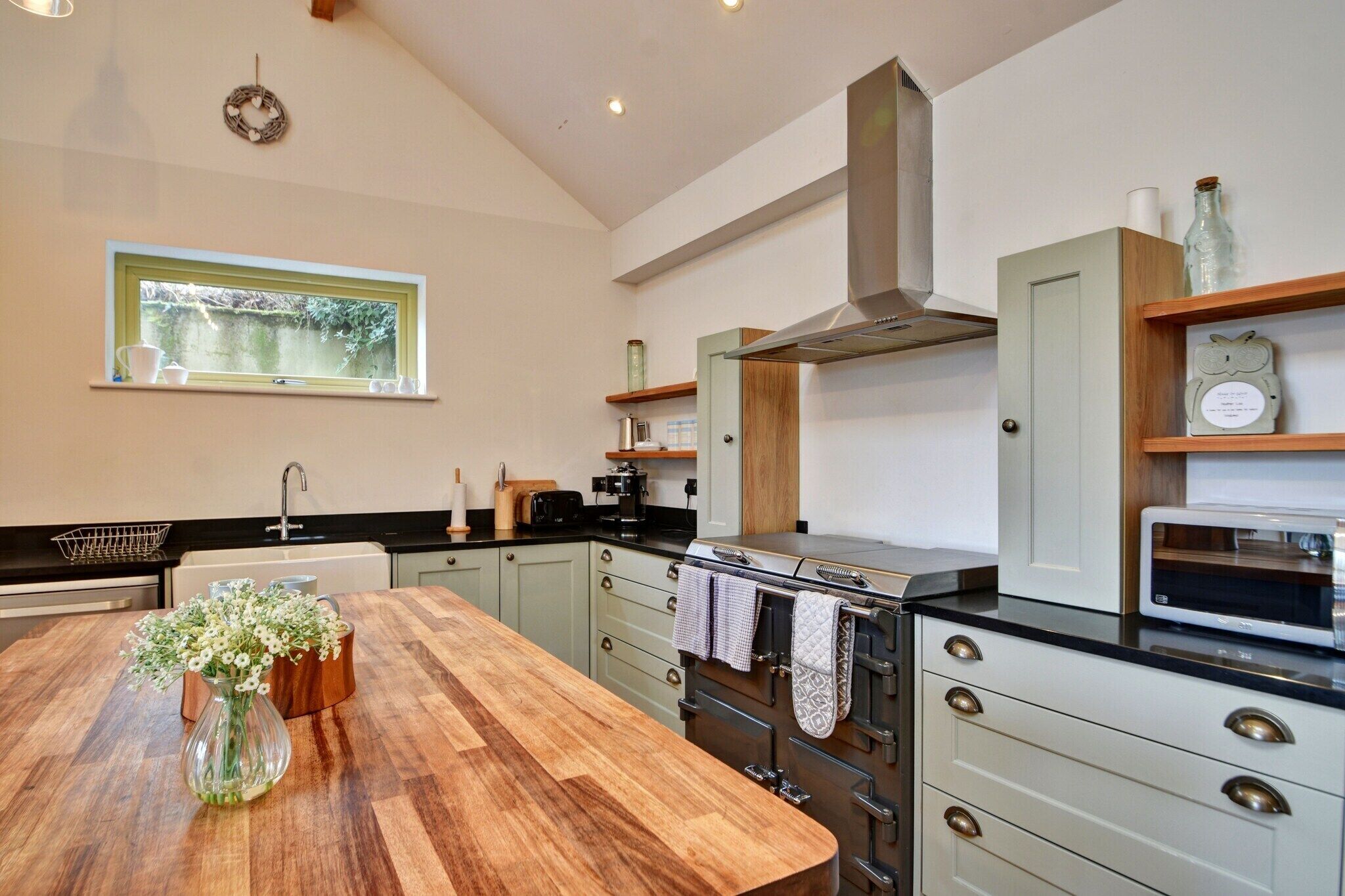 A modern kitchen with a wooden table, built-in oven, and stainless steel appliances.