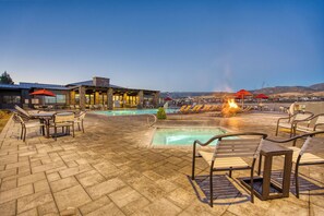 A poolside area with lounge chairs, a fire feature, and a building with large windows. - Verde Ranch RV Resort (Camp Verde)