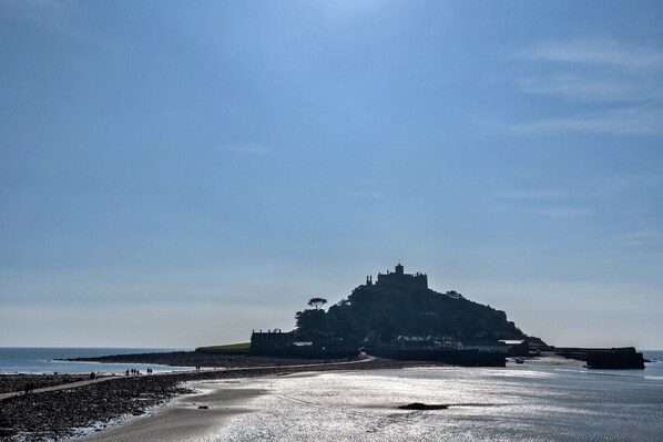 A coastal castle with a beach in the foreground.