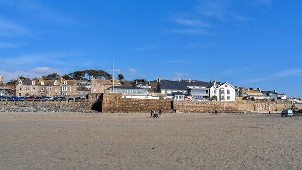A coastal town with stone buildings, a sandy beach, and a clear blue sky.