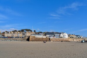 A coastal town with stone buildings, a sandy beach, and a clear blue sky.