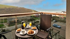 A balcony with breakfast setup overlooking a coastal view. - Apartment in Watergate Bay with Sea Views (Watergate Bay)