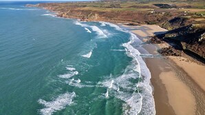 An aerial view of a coastal area with a sandy beach and rocky cliffs.