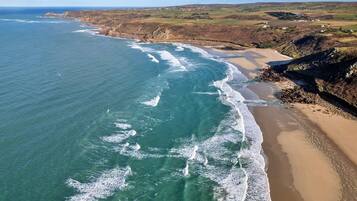 An aerial view of a coastal area with a sandy beach and rocky cliffs.