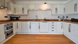 A modern kitchen with white cabinets, stainless steel appliances, and wooden countertops. - Cottage in Cornwall near Bodmin Moor (St Breward)