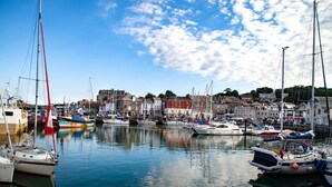 A marina with various boats docked, surrounded by buildings and a clear sky.