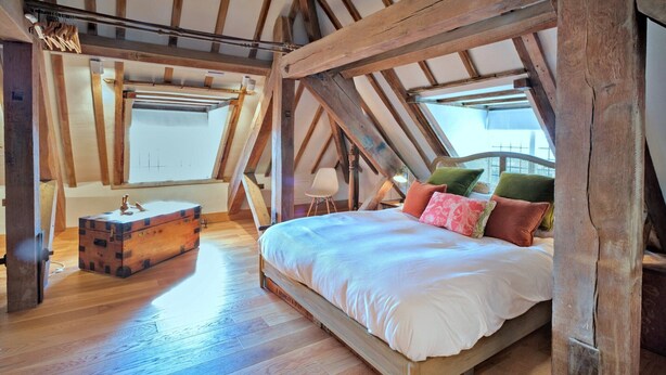 A bedroom with a wooden bed, a chest of drawers, and a window with a view. - Apartment in Brackley Town Hall Charm (Brackley)