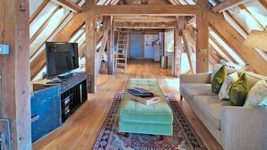 A cozy attic room with a television, a sofa, and a patterned rug. - Apartment in Brackley Town Hall Charm (Brackley)