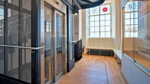 A modern interior with a wooden floor, glass doors, and a bench. - Apartment in Brackley Town Hall Charm (Brackley)