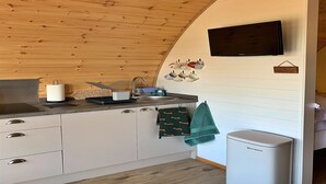 A kitchen with a wooden ceiling, a sink, a stove, and a microwave.