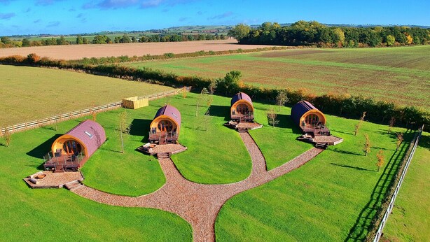 A rural property with four round-roofed cottages connected by a central gravel path.