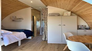 A bedroom with a bed, a bedside table, a wardrobe, and a dining area with a table and chairs.