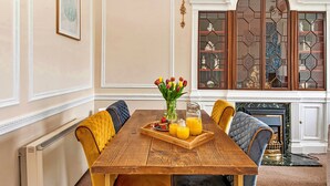 A dining area with a wooden table, yellow and gray upholstered chairs, a tray with fruit and orange juice, and a vase with tulips. - Lodge in Thirsk with Spa & Scenic Trails (Thirsk)