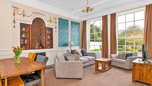 A spacious living room with a wooden dining table, two sofas, a coffee table, and a television on a wooden cabinet. - Lodge in Thirsk with Spa & Scenic Trails (Thirsk)