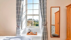A bedroom with a large window, a bedside table with a tray of breakfast, a bed with a blanket, a wooden wardrobe, and a mirror on the wall. - Lodge in Thirsk with Spa & Scenic Countryside (Thirsk)