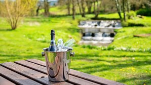 A metallic bucket with a bottle and glasses on a wooden table in a park. - Lodge in Thirsk with Spa & Scenic Countryside (Thirsk)