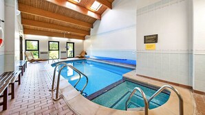 An indoor swimming pool with wooden beams, a tiled floor, and a bench area. - Lodge in Thirsk with Spa & Scenic Trails (Thirsk)