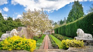 A garden pathway leading to a building with a brick facade, surrounded by manicured hedges and statues. - Lodge in Thirsk with Spa & Scenic Trails (Thirsk)