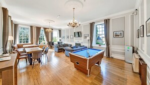Un vaste salon comprenant une table de billard, un coin repas et un ensemble de canapés.