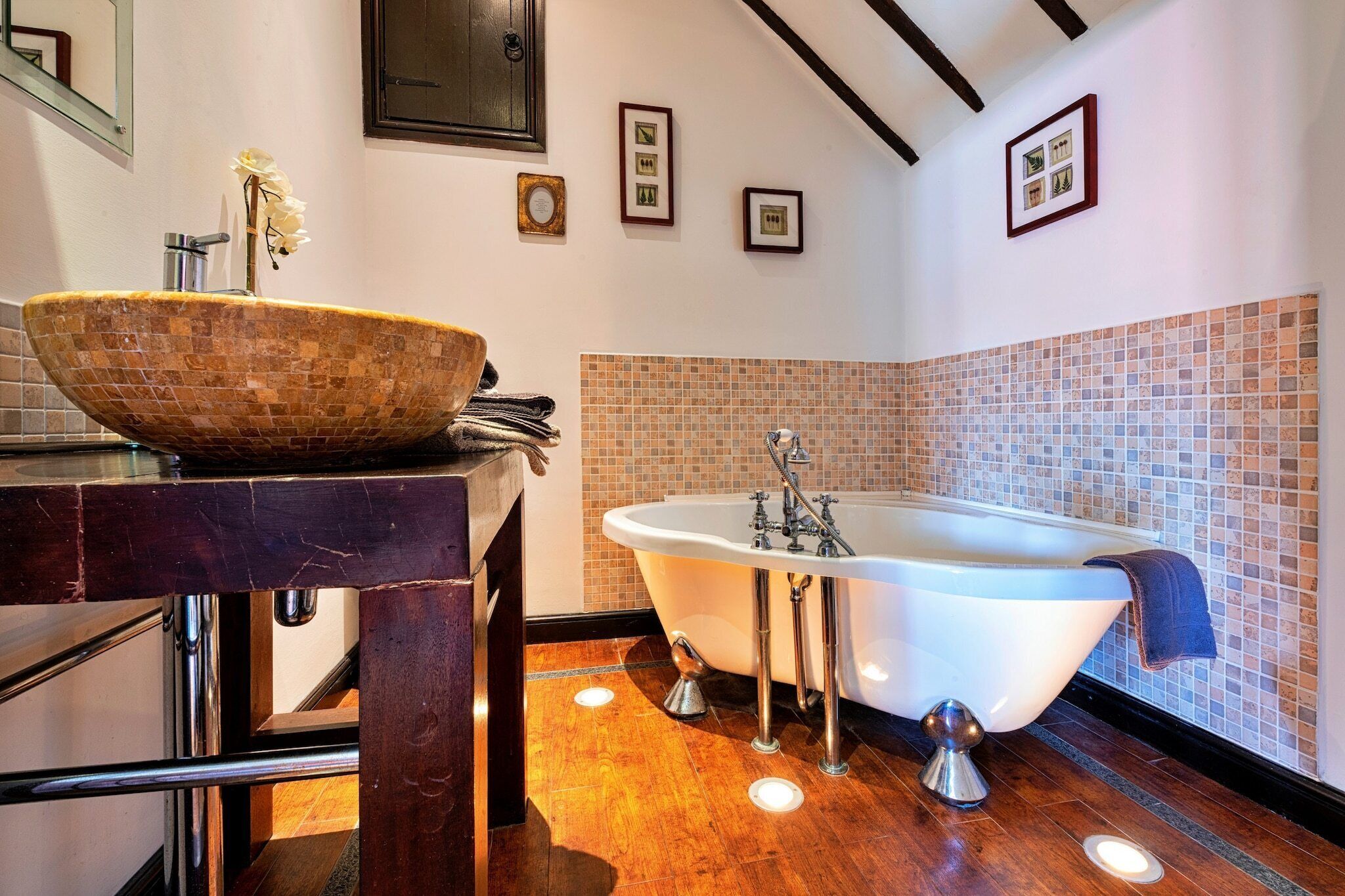A bathroom with a freestanding bathtub, a wooden basin sink, and a tiled backsplash.