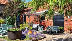 A courtyard with outdoor seating, a brick building, and a pergola. - Barn in Lincolnshire near Historic Newark (Newark)