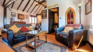 A traditional room with exposed wooden beams, a black leather sofa, a wooden coffee table, and a patterned rug. - Barn in Lincolnshire near Historic Newark (Newark)