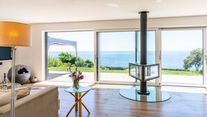 A modern living room with a large glass door leading to a balcony with a view of the sea.