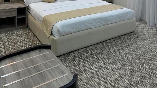 Camera d'albergo moderna con un letto grande, un tavolino rotondo e un pannello decorativo a parete.