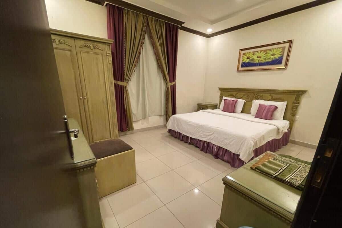 A hotel room with a bed, a small desk, a wardrobe, and a bathroom.
